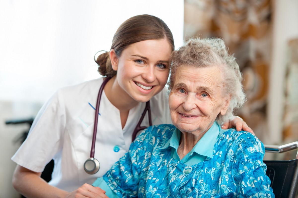 A senior and a nurse smiling into the camera.