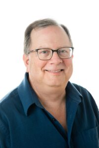 Photo of smiling man wearing glasses in blue shirt