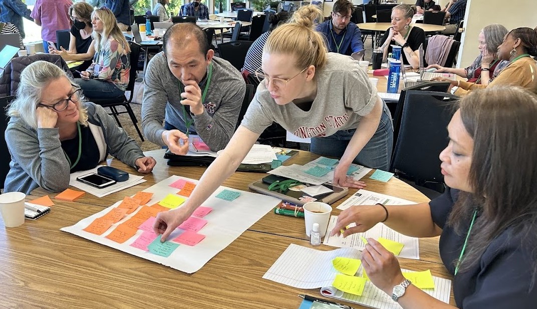 Four people working at a table with colorful sticky notes